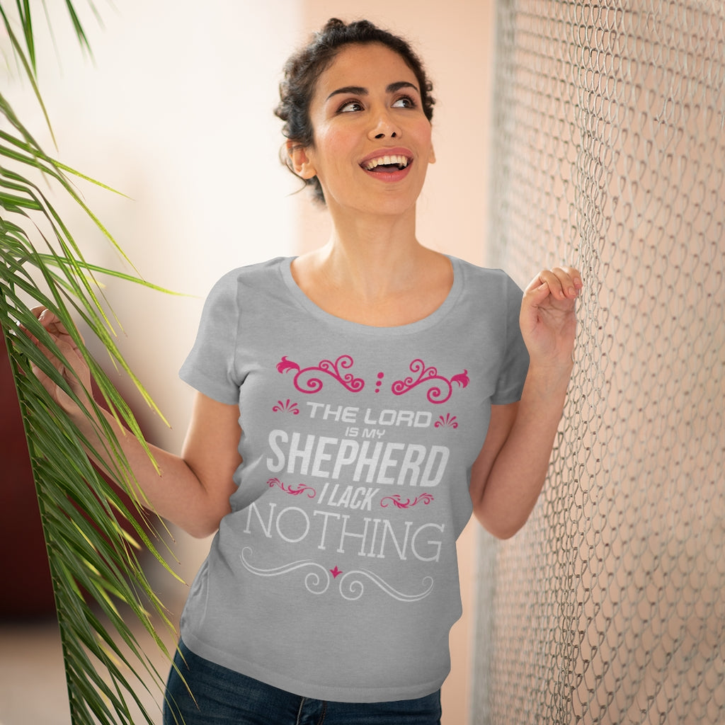 There is a smiling lady wearing a gray shirt with white writing and pink embroidery surrounding it at the top and white embroidery surrounding it at the bottom.  A shirt that states the following "The Lord is my shepherd I lack Nothing". This is from Psalm 23. 
